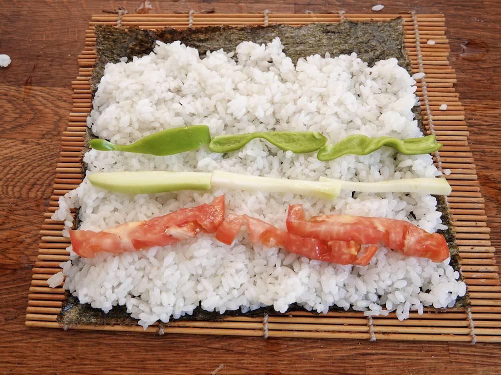 Enrollar los Maki sushi: arroz y verduritas sobre esterilla